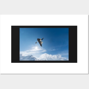 Snowboarder jumping against blue sky Posters and Art